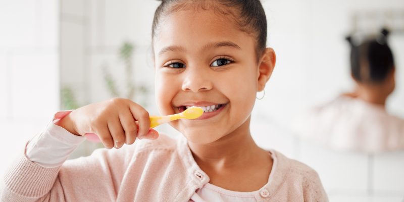 Child, toothbrush and brushing teeth in a home bathroom for dental health and wellness with smile. Face portrait of african girl kid cleaning mouth with a brush for morning routine and oral self care.